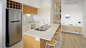A modern kitchen with a central island, stainless steel appliances, and a minimalist design. - Bay Vue - Absolute Oceanviews! (Apollo Bay)