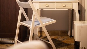 Habitación pequeña con escritorio, silla y ventana con cortinas.