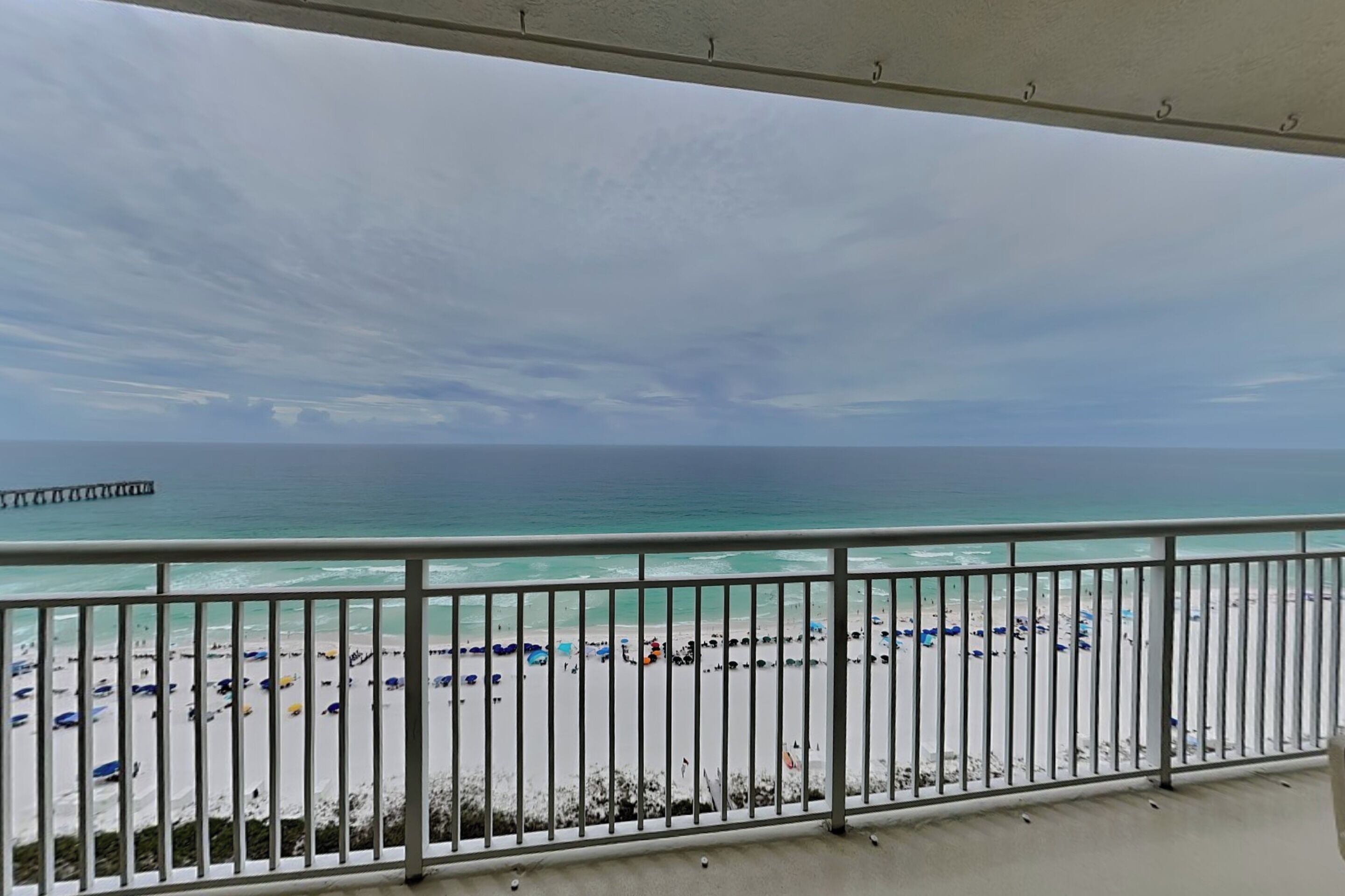 A balcony with a view of a beach and a pier.