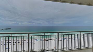 A balcony with a view of a beach and a pier.