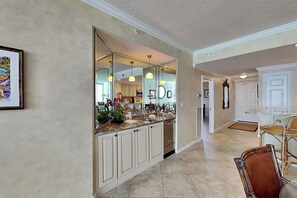 A kitchen with a large island, white cabinetry, and a mirrored backsplash. - The Pearl of Navarre #1505 by Southern Vacation Rentals (Navarre)
