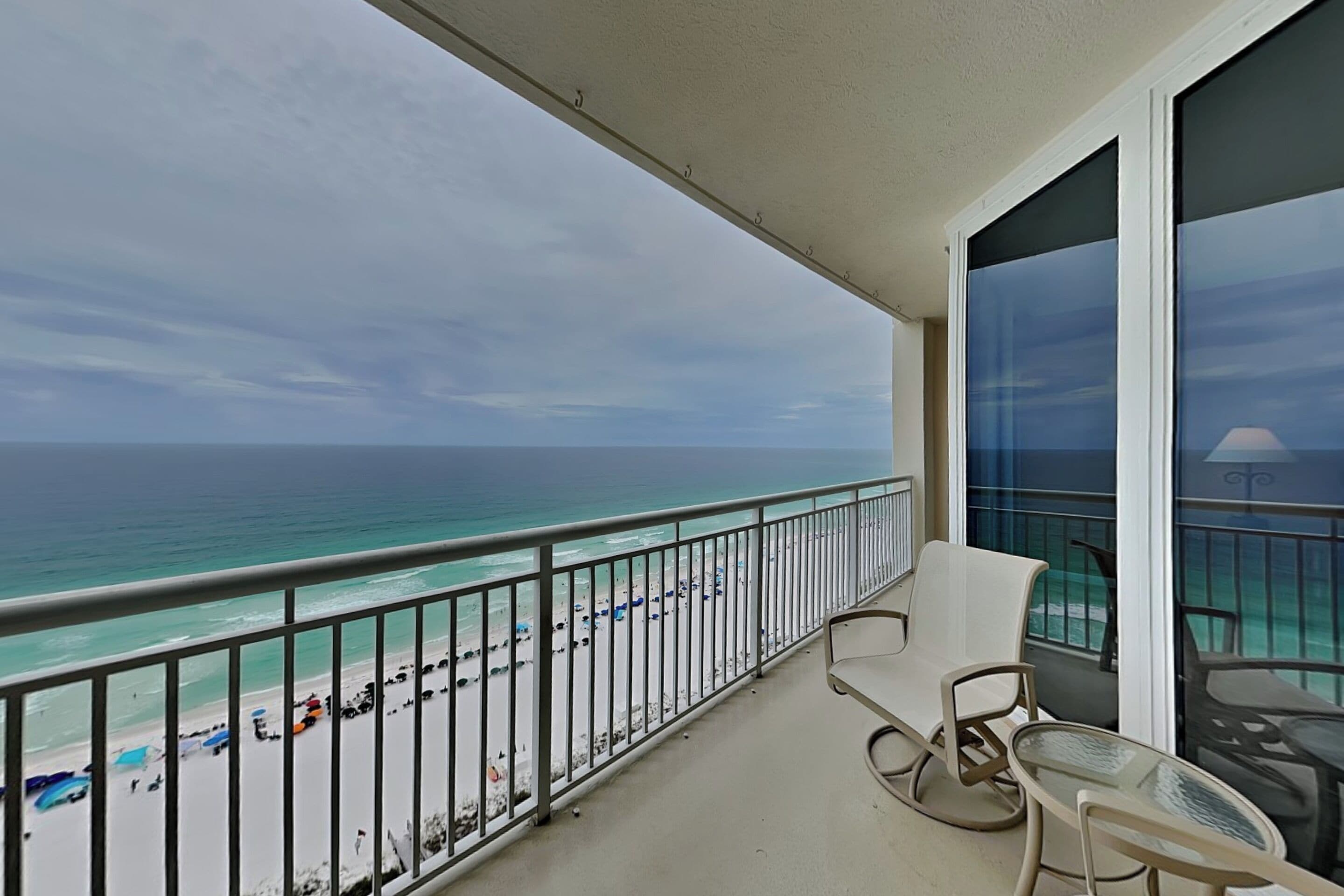 A balcony with a view of the beach and ocean.