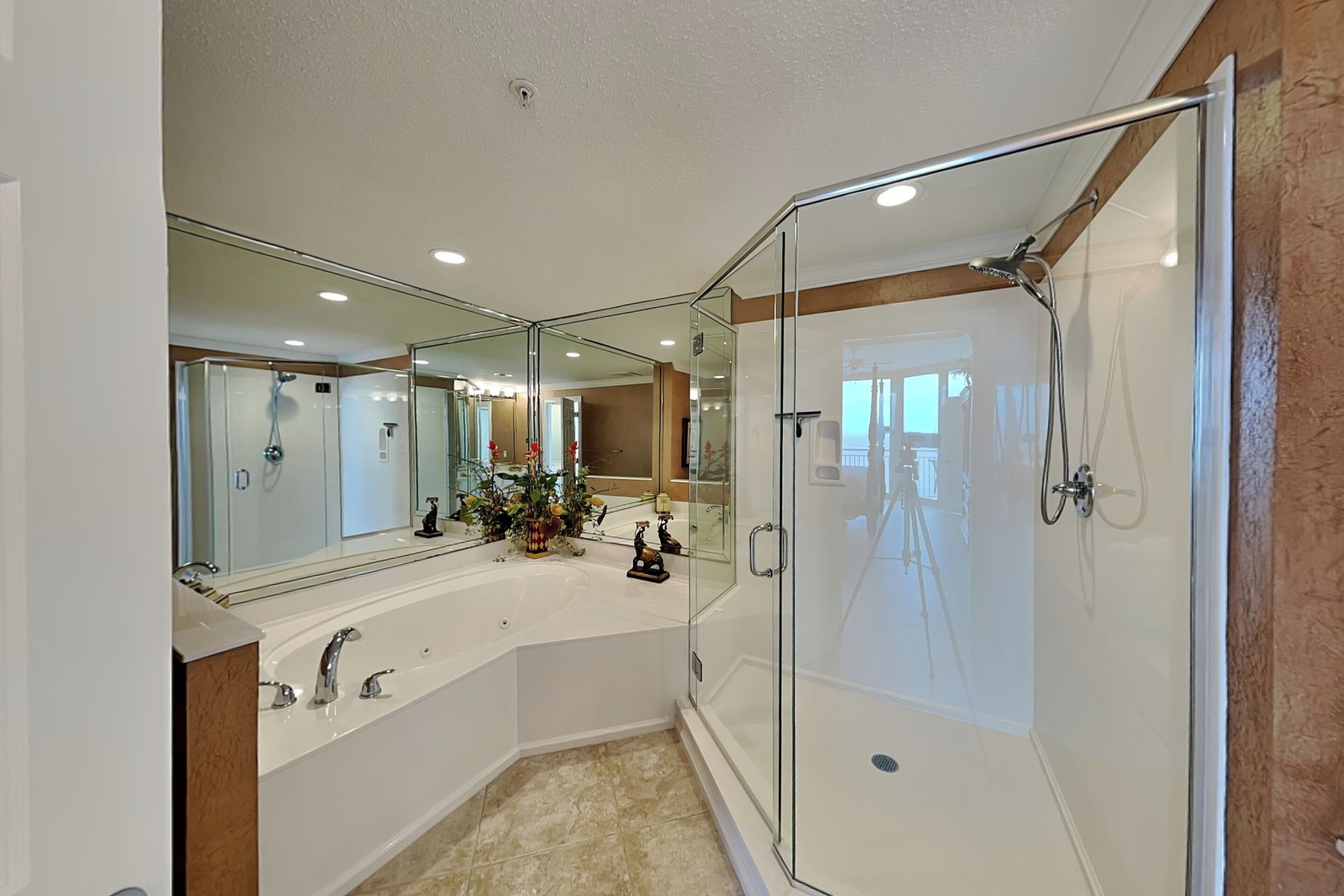 A modern bathroom with a glass-enclosed shower, a large mirror, and a white vanity.
