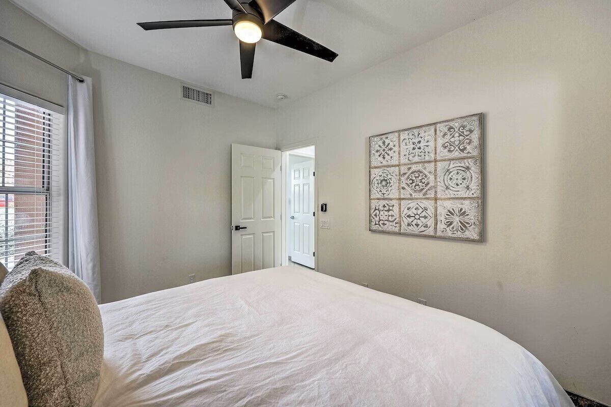 Une chambre à coucher comprenant un lit, un ventilateur de plafond, une porte et un panneau décoratif mural.