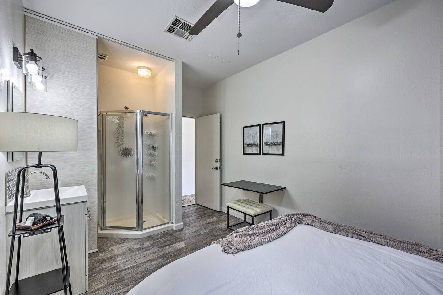 Ein modernes Schlafzimmer mit Bett, Schreibtisch, Stuhl, Dusche und Bad.