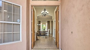 A hallway with a welcome mat, a chandelier, and a dining area with a table and chairs. - Hello Sunshine! Private Heated Pool Included! (Scottsdale)