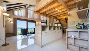 Un'ampia cucina con travi in legno, un'isola grande e un balcone con posti a sedere esterni.
