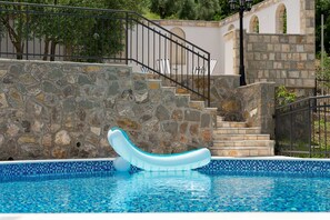 Una scala di pietra conduce a una zona piscina con un galleggiante gonfiabile blu e bianco.