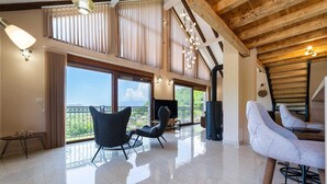 Un'ampia zona giorno con soffitto alto, grandi finestre e vista sull'esterno.