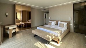 A modern hotel room with a large bed, a seating area, and a walk-in closet. - Villa Mila with Pool (Budva)