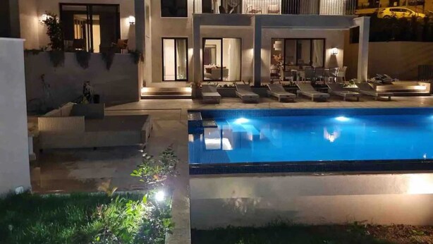 A modern two-story house with a swimming pool, outdoor seating, and a well-lit balcony. - Villa Mila with Pool (Budva)