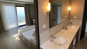 A hotel room with a large bed, a bathroom with a sink and mirror, and a balcony with curtains. - Villa Mila with Pool (Budva)