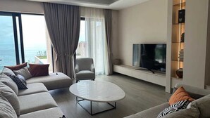 A modern living room with a large sofa set, a coffee table, a TV, and a view of the sea. - Villa Mila with Pool (Budva)