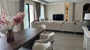 A modern living room with a sofa set, a flat-screen TV, and a dining area with a table and chairs. - Villa Mila with Pool (Budva)