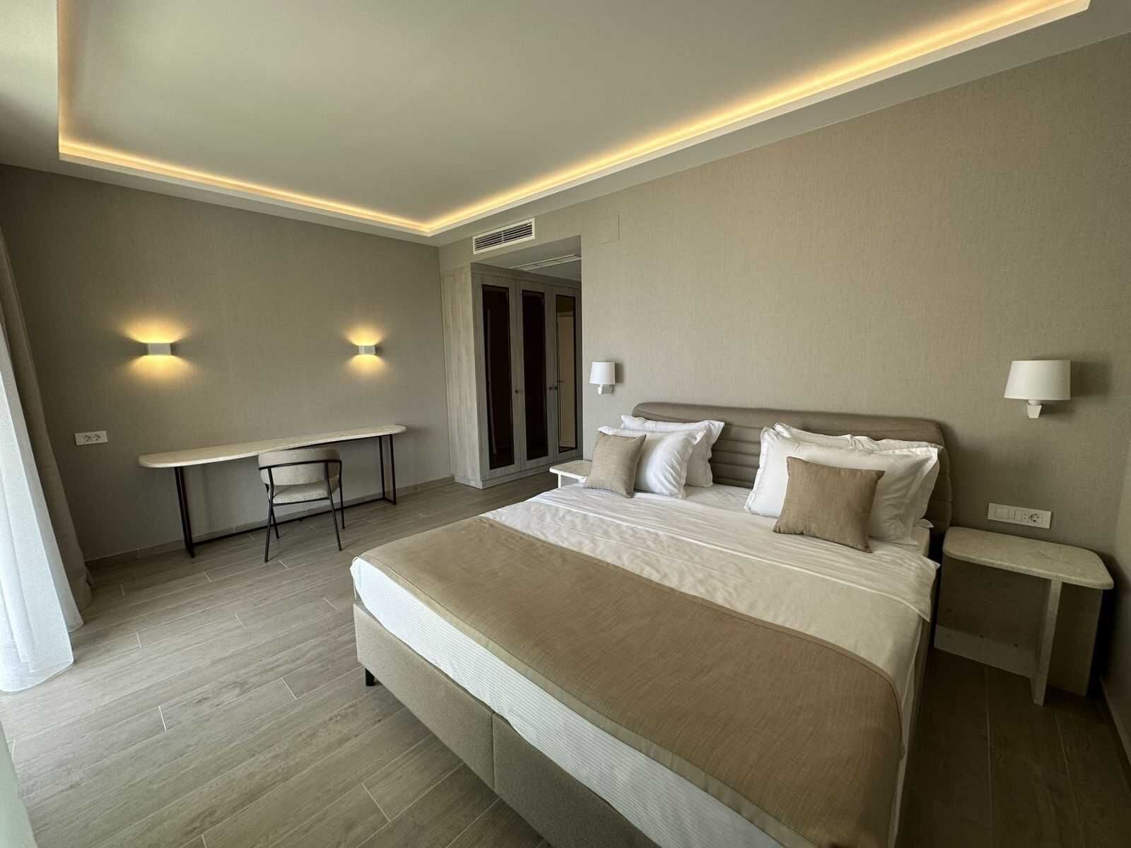Een moderne hotelkamer met een groot bed, een bureau en twee wandlampen.