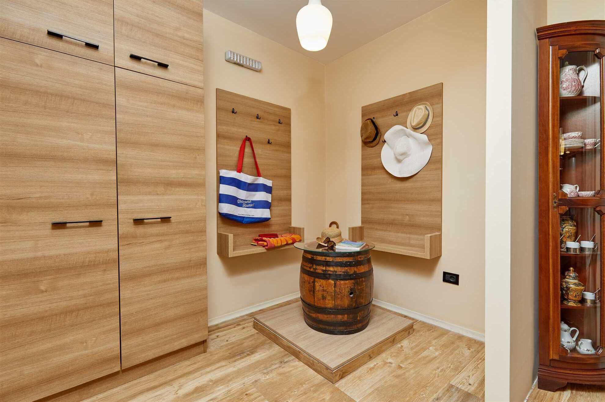 A hallway with wooden cabinets, a small table with a hat, and a decorative cabinet with glass doors.