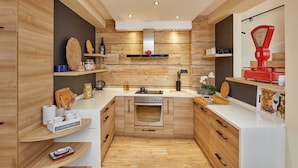 Eine moderne Küche mit Holzschränken, einem eingebauten Backofen und einem roten Gerät auf der rechten Seite.