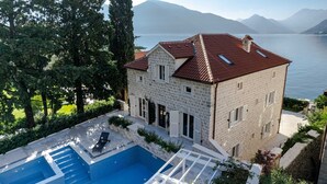Une maison en pierre avec une piscine et une vue sur le lac et les montagnes.