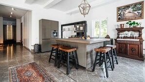 Une cuisine moderne dotée d’un îlot central, de tabourets de bar, d’un réfrigérateur et d’un meuble décoratif.