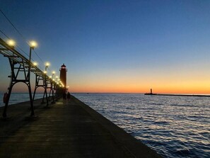 A pier with a lighthouse at the end, extending into the water. - Family Retreat at Village Farmhouse - Near Grand Haven Beach (Spring Lake)