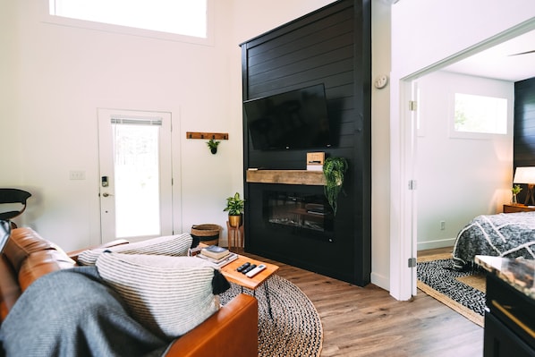Una sala de estar moderna con chimenea, un sofá, una mesa de centro y una televisión.