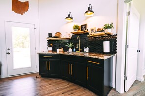 A kitchen with black cabinets, a granite countertop, and two pendant lights.