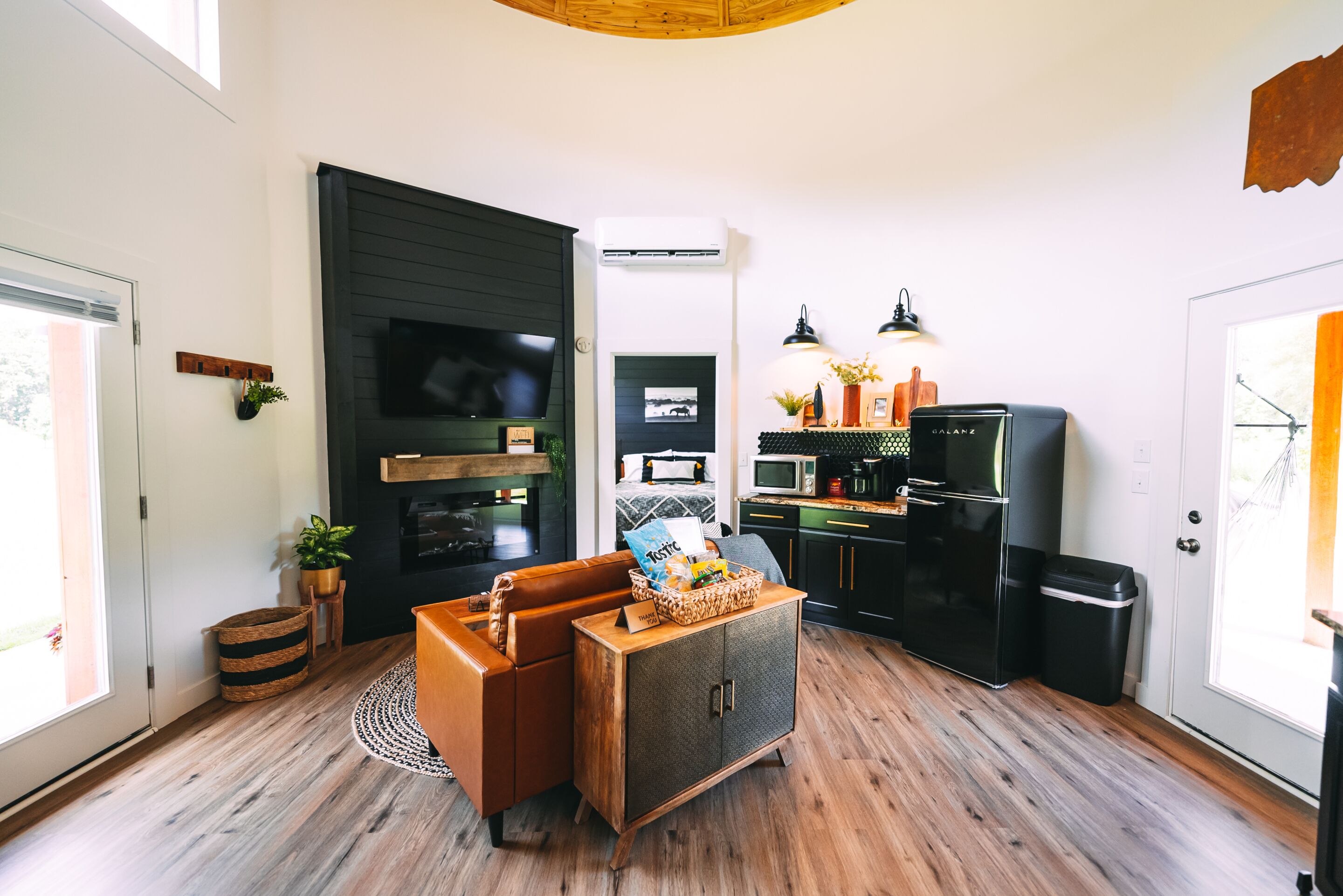 Um espaço compacto com cozinha compacta, sofá, mesa de jantar e televisão na parede.