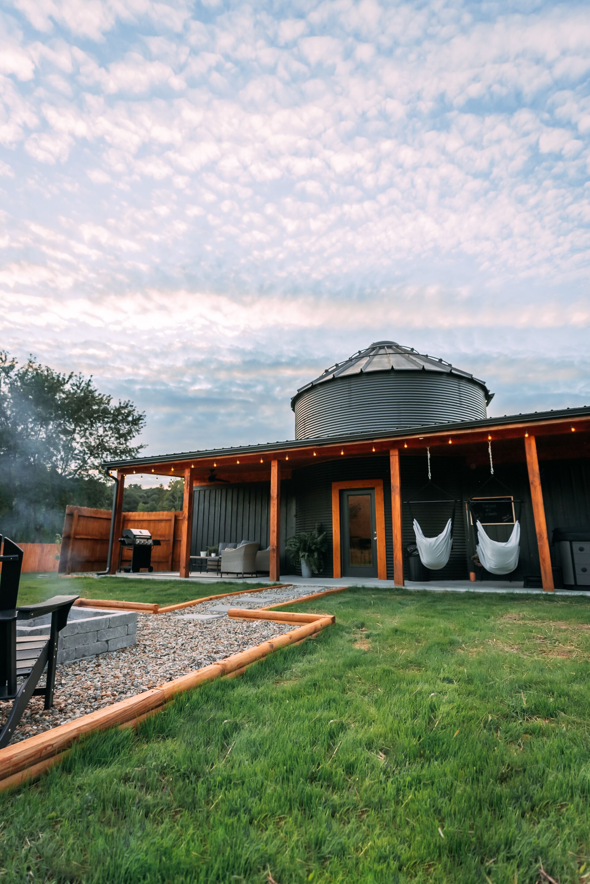 A modern outdoor patio with a grill, seating, and a water feature.