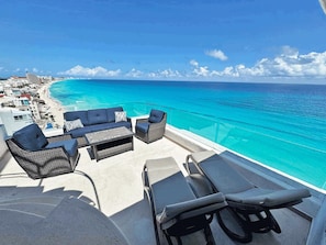 Varanda com mobiliário de exterior com vista para uma praia e oceano.