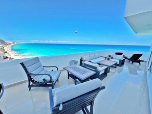 Un balcón con mobiliario exterior con vistas a una playa y al océano.
