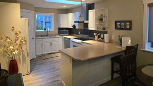 A modern kitchen with white cabinets, a central island, and a skylight. - A Walk to the Harborfront  (Nanaimo)