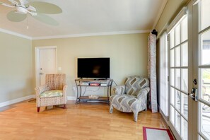 Relax in this inviting living room with a flat-screen TV, two comfortable armchairs, and a door leading to an outdoor area.