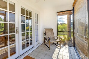 Relax in an outdoor space with a cushioned chair and French doors leading to lush surroundings.