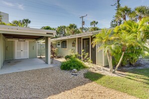 A two-story building with a covered driveway and a small garden area with palm trees. - Manasota Key Vacation Rental w/ Beach Access! (Englewood)