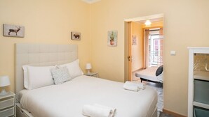 A hotel room with a large bed, a nightstand, a lamp, and a door leading to a balcony. - Cozy 1-bedroom Apt|Historic location by Lisbeyond (Lisboa)