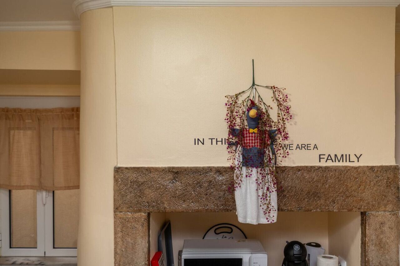 A kitchen with a decorative hanging above a fireplace, a microwave, and a coffee maker on the counter.