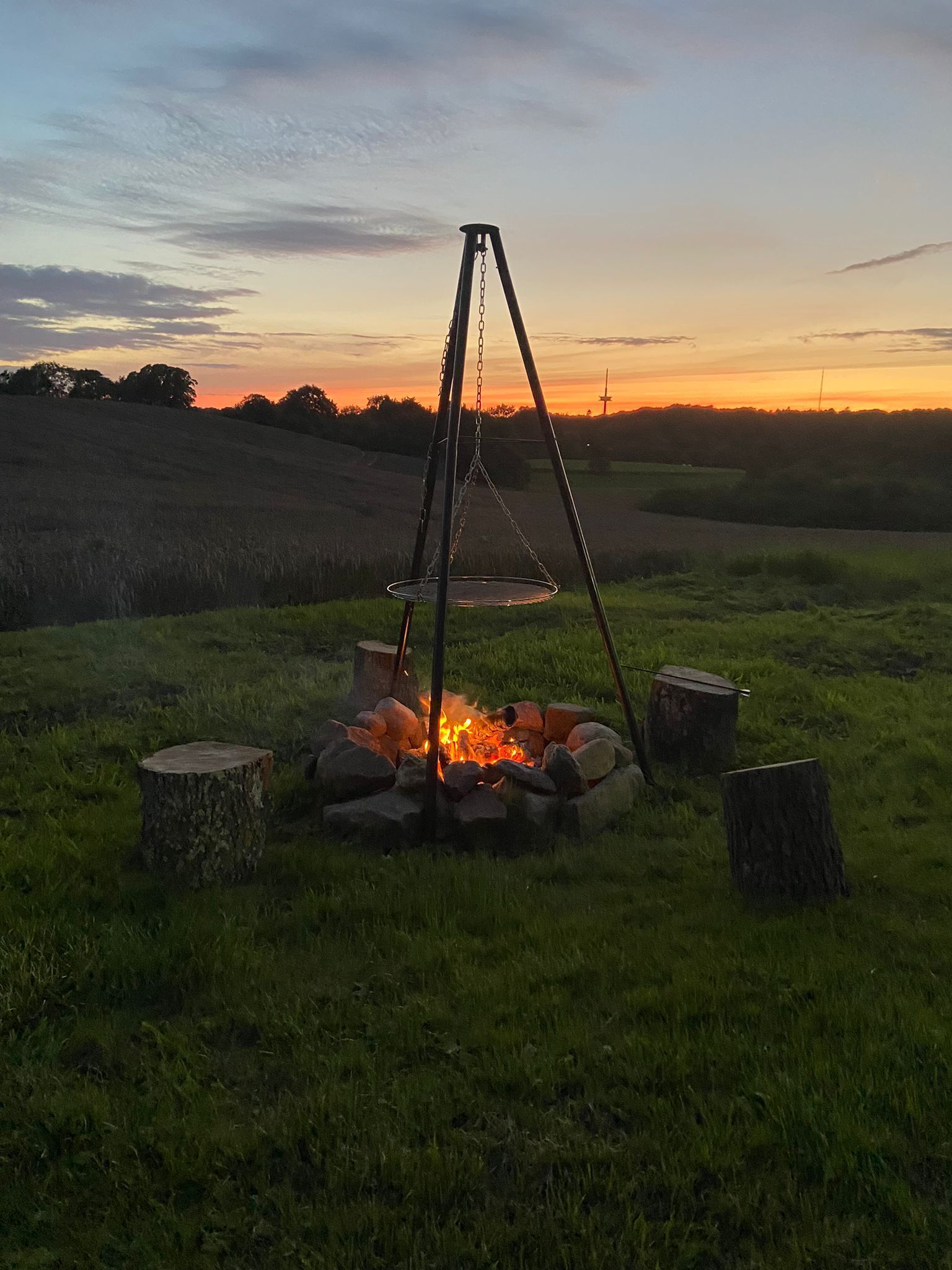 Een kampvuur met een schommel in een grasveld bij zonsondergang.