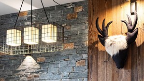 Un comedor rústico con pared de piedra, vigas de madera y un trofeo de caza.