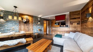Una sala moderna con pared de piedra, detalles de madera, una cabeza de ciervo montada, un comedor con mesa de madera y un sofá blanco.