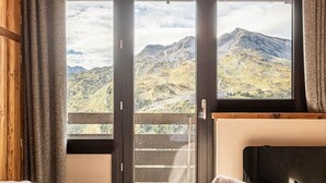 Un dormitorio con cama, vistas a las montañas a través de un ventanal y una lámpara colgante.