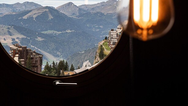 Una ventana redonda con vistas a montañas y edificios.