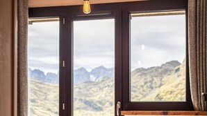 Un dormitorio con una cama, una ventana y vistas a montañas.