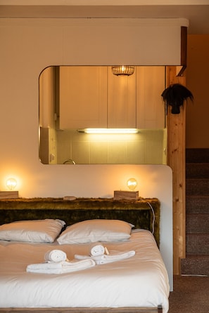 A hotel room with a bed, two bedside lamps, a mirror, and a headboard.