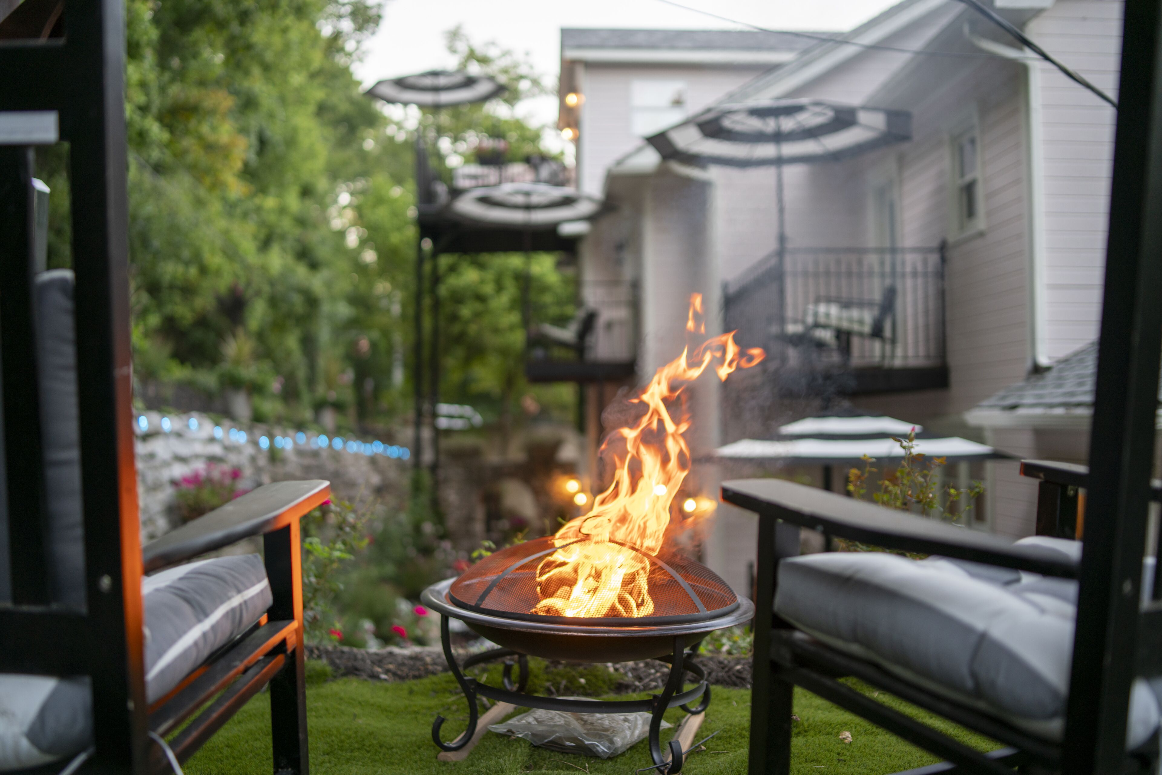 A patio with a fire feature, outdoor furniture, and a view of a house.