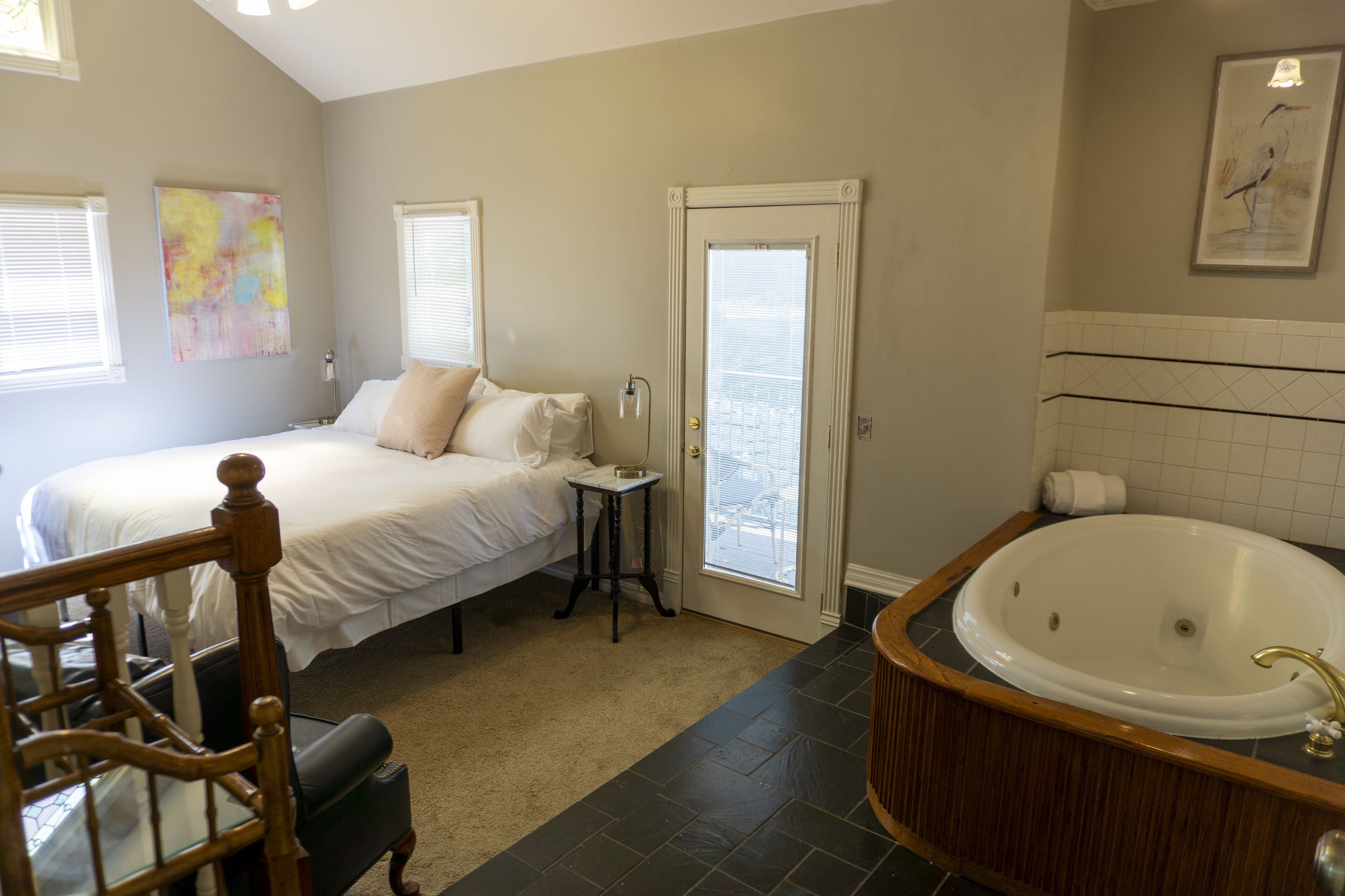 Une chambre à coucher comprenant un lit, une table de chevet, une fenêtre et une salle de bain avec une baignoire.