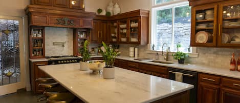 A spacious kitchen with a large island, wooden cabinets, and bar stools.