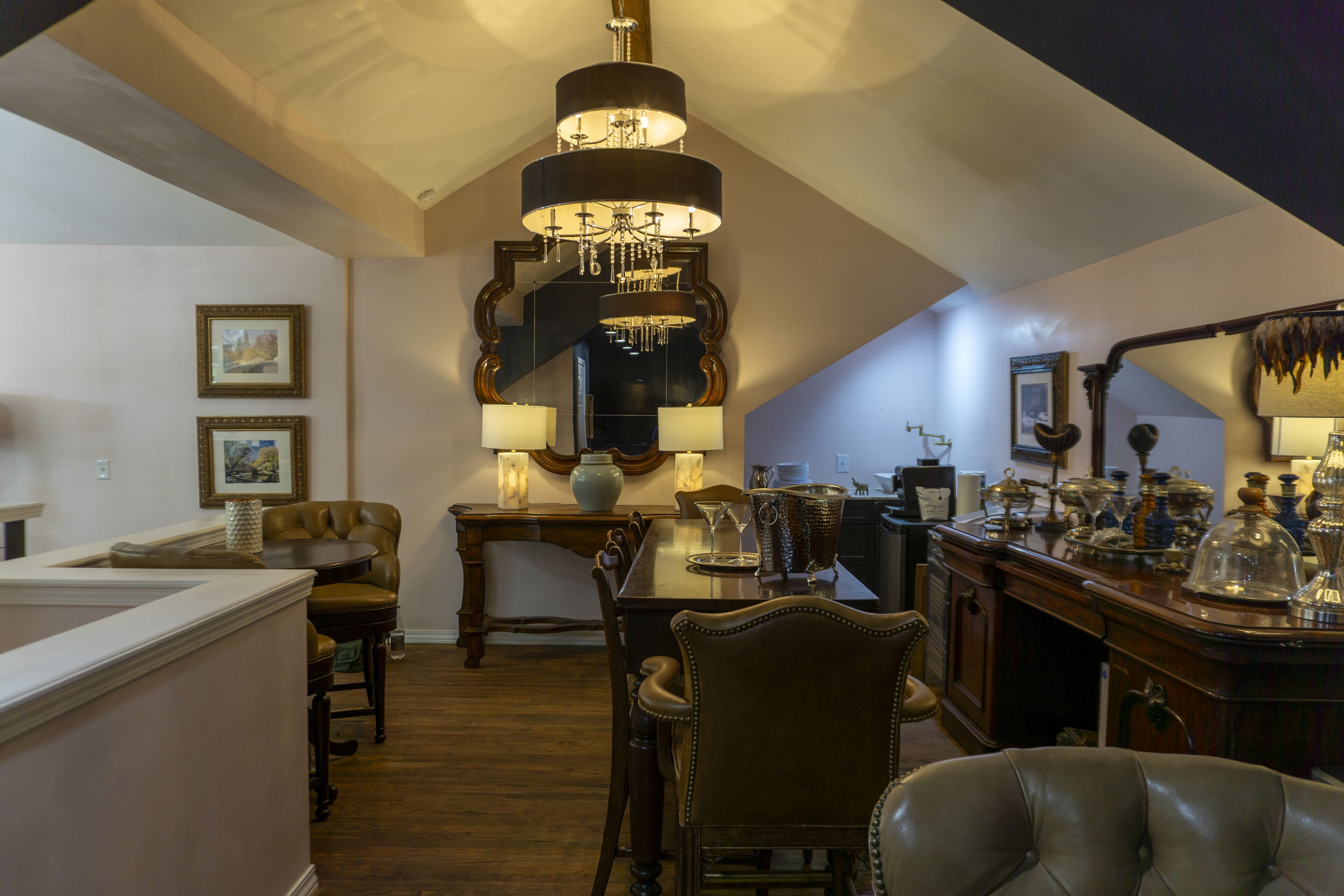 Uma sala de jantar com um candelabro, móveis de madeira e um bar com copos.