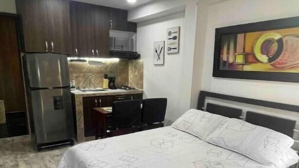 Une chambre d’hôtel de taille réduite, comprenant un lit, une petite kitchenette et un coin repas.