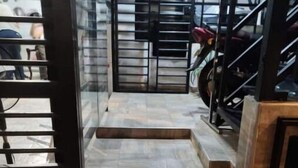 Un escalier menant à un garage doté d’une porte métallique et où est garée une moto.