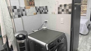 Une petite buanderie équipée d’un lave-linge, d’un sèche-linge et d’un radiateur.